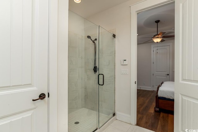 bathroom with a ceiling fan, connected bathroom, a shower stall, wood finished floors, and baseboards