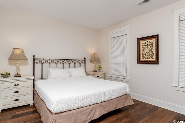 bedroom with dark wood-style flooring, visible vents, and baseboards