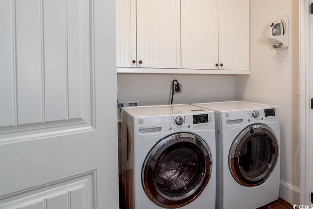 clothes washing area with cabinets and washer and clothes dryer