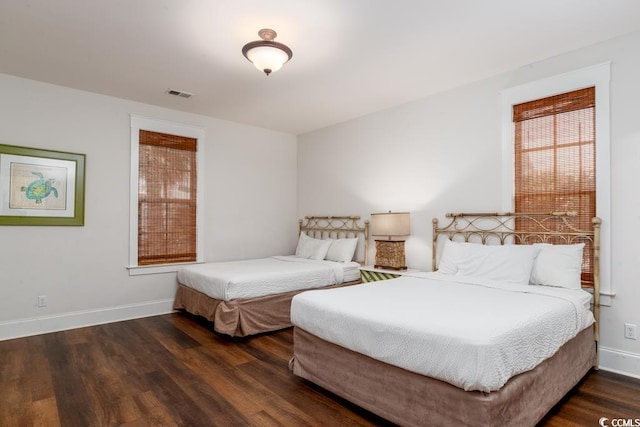 bedroom with visible vents, baseboards, and wood finished floors