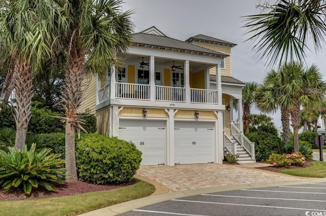 beach home featuring metal roof, a garage, a ceiling fan, stairs, and decorative driveway