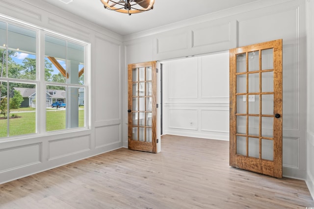 empty room with french doors, a healthy amount of sunlight, and light hardwood / wood-style flooring