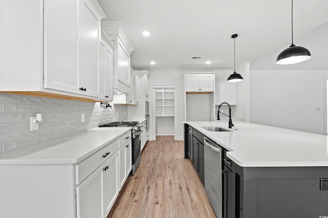 kitchen with stainless steel appliances, sink, hanging light fixtures, white cabinets, and light wood-type flooring