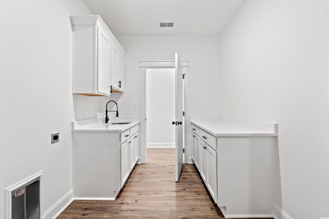 kitchen with white cabinetry, sink, and light hardwood / wood-style flooring