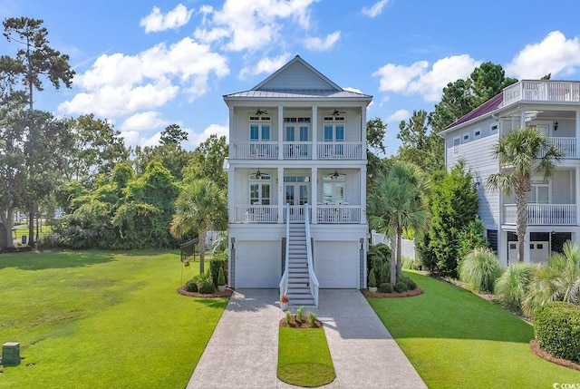 coastal home featuring driveway, a front lawn, a ceiling fan, a porch, and stairway