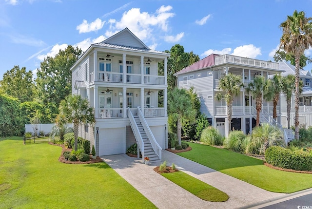 coastal home featuring a front lawn, covered porch, concrete driveway, a balcony, and stairs