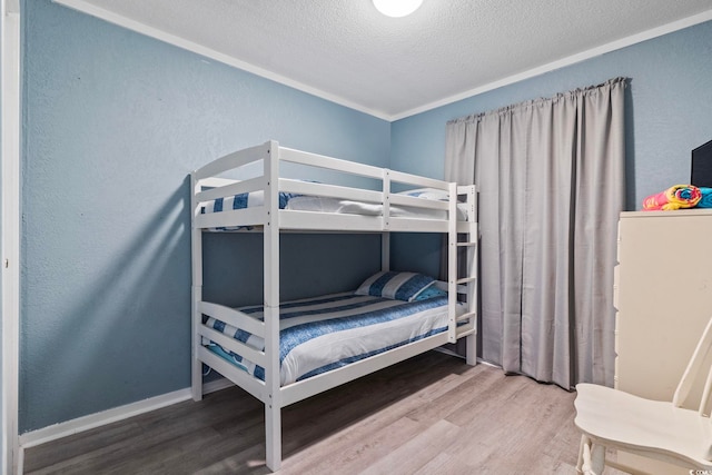 bedroom with a textured ceiling, crown molding, and hardwood / wood-style flooring