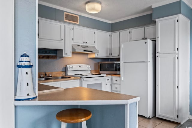 kitchen with white appliances, a textured ceiling, a kitchen bar, kitchen peninsula, and sink