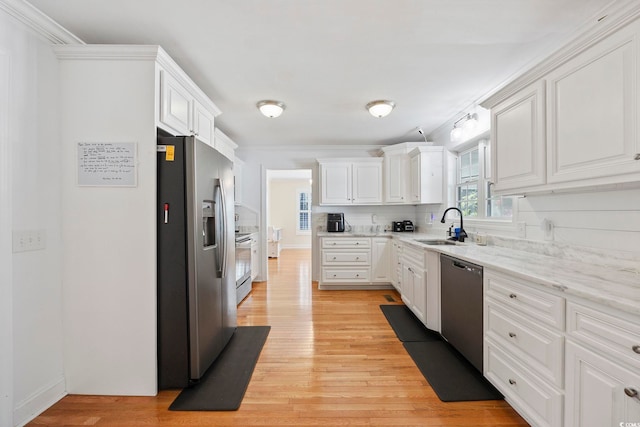 kitchen with white cabinets, light hardwood / wood-style flooring, light stone countertops, stainless steel appliances, and sink