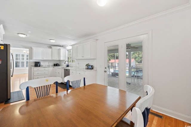 dining room featuring ceiling fan, ornamental molding, sink, and light wood-type flooring