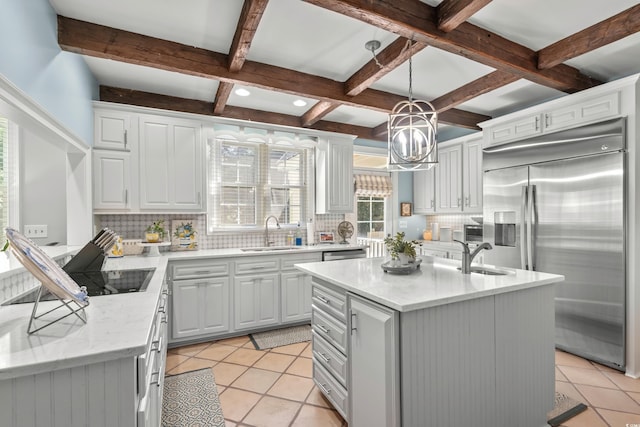 kitchen with a kitchen island with sink, sink, decorative backsplash, decorative light fixtures, and stainless steel appliances