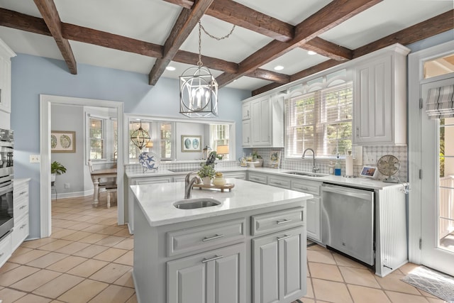 kitchen featuring backsplash, a kitchen island with sink, white cabinets, sink, and appliances with stainless steel finishes