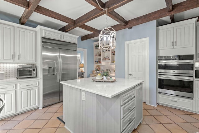 kitchen featuring decorative backsplash, appliances with stainless steel finishes, white cabinetry, and a kitchen island