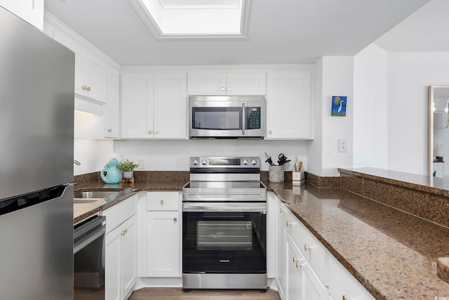 kitchen with dark stone countertops, white cabinetry, and appliances with stainless steel finishes