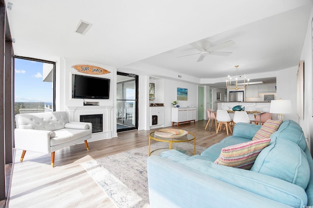 living room featuring ceiling fan with notable chandelier and light hardwood / wood-style floors