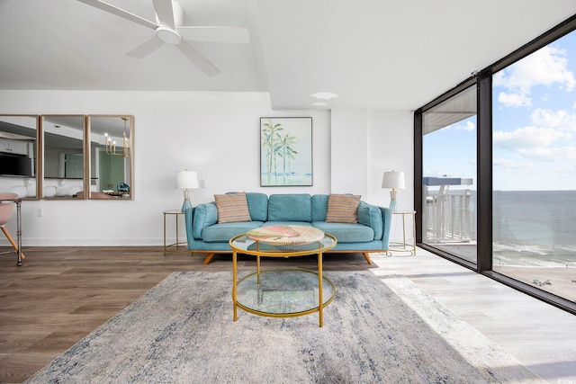 living room featuring wood-type flooring, floor to ceiling windows, a water view, and ceiling fan