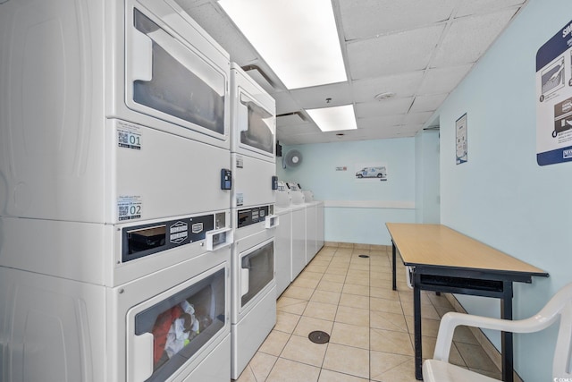 kitchen with a drop ceiling, light tile patterned floors, and stacked washer and clothes dryer