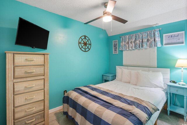 bedroom featuring light tile patterned flooring, ceiling fan, and a textured ceiling