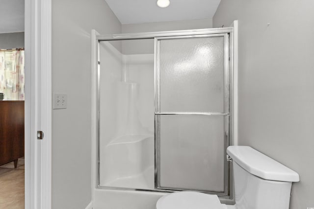 bathroom featuring a shower with shower door and toilet