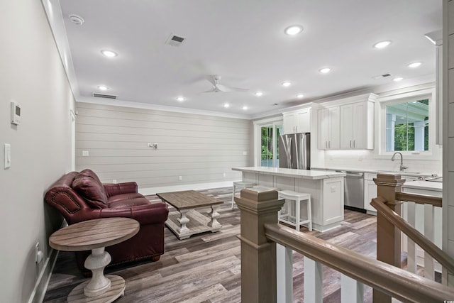 living room with hardwood / wood-style floors, ceiling fan, crown molding, and sink