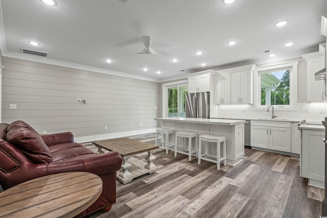 living room featuring light wood-type flooring, ceiling fan, plenty of natural light, and sink