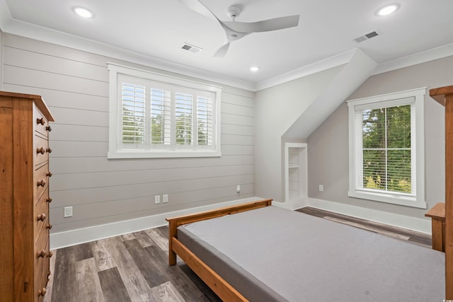 bedroom with crown molding, dark hardwood / wood-style flooring, wood walls, and ceiling fan