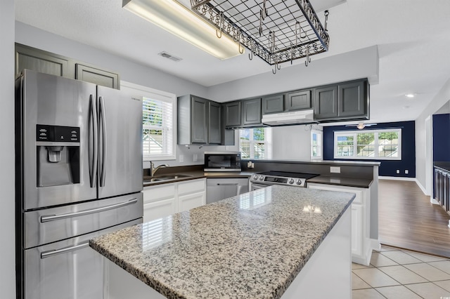 kitchen with sink, kitchen peninsula, gray cabinets, stainless steel appliances, and light hardwood / wood-style floors