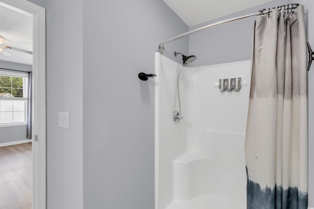 bathroom with a textured ceiling, hardwood / wood-style flooring, ceiling fan, and curtained shower