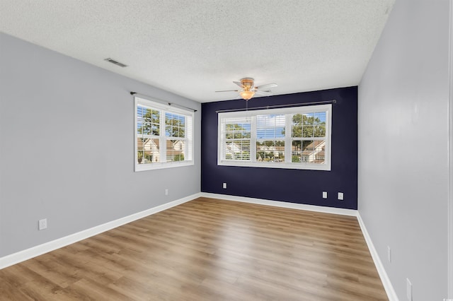 spare room with light wood-type flooring, ceiling fan, and a textured ceiling