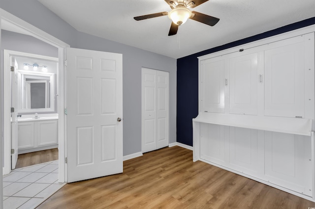 unfurnished bedroom featuring light hardwood / wood-style floors, vaulted ceiling, ensuite bath, and ceiling fan