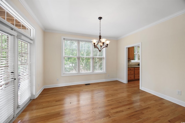 unfurnished dining area featuring crown molding, wood-type flooring, and a chandelier