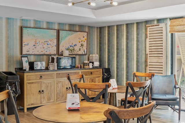 dining area with a raised ceiling and light hardwood / wood-style floors