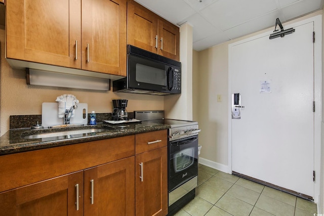 kitchen with stainless steel range with electric stovetop, dark stone counters, light tile patterned floors, and sink