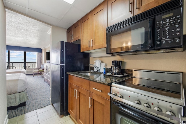 kitchen featuring black appliances, light tile patterned floors, sink, and dark stone counters