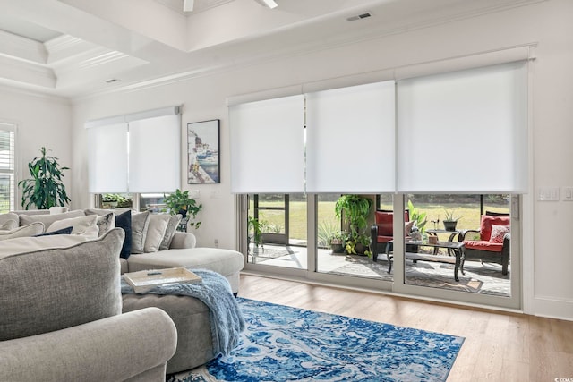 living room featuring crown molding, light hardwood / wood-style flooring, and a healthy amount of sunlight