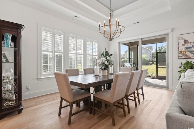 dining area with light hardwood / wood-style floors, crown molding, an inviting chandelier, and plenty of natural light