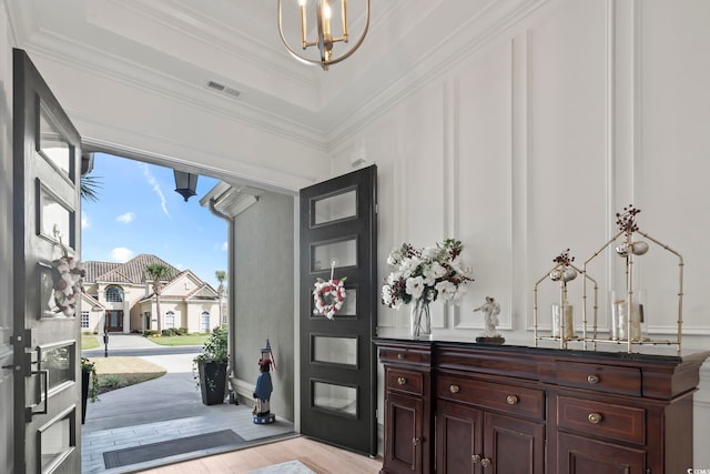 entrance foyer with an inviting chandelier, crown molding, and light hardwood / wood-style floors