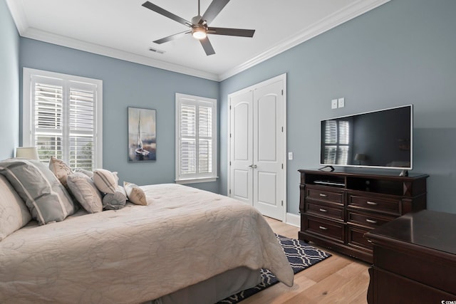 bedroom featuring a closet, ceiling fan, ornamental molding, and light wood-type flooring