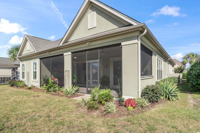 back of property featuring a lawn and a sunroom