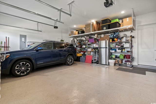 garage with a garage door opener and stainless steel fridge