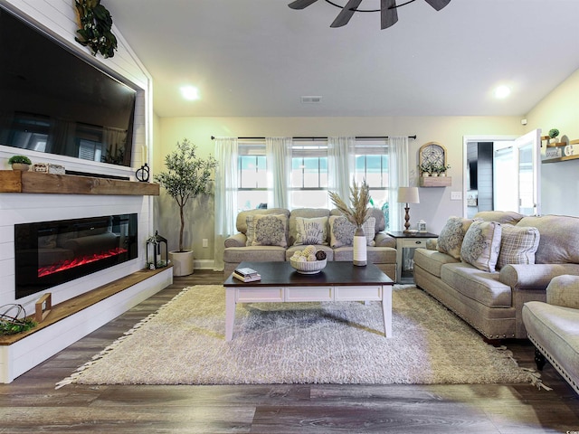 living room with visible vents, a glass covered fireplace, dark wood-style floors, ceiling fan, and vaulted ceiling