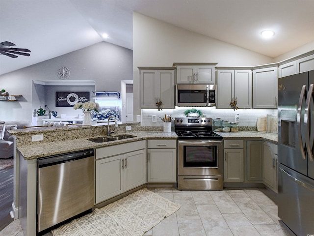 kitchen with open floor plan, a peninsula, vaulted ceiling, stainless steel appliances, and a sink