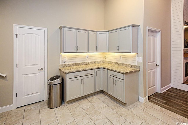 kitchen with light stone counters, baseboards, a high ceiling, and decorative backsplash