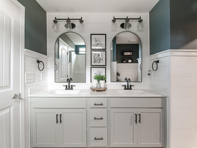 full bathroom with a sink, tile walls, and double vanity