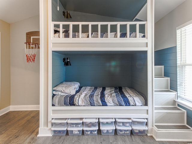 bedroom featuring baseboards, vaulted ceiling, and wood finished floors