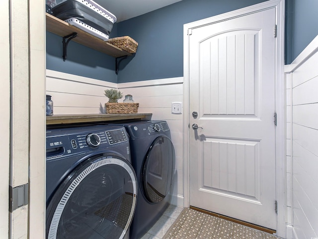 washroom with laundry area, washer and dryer, and a wainscoted wall