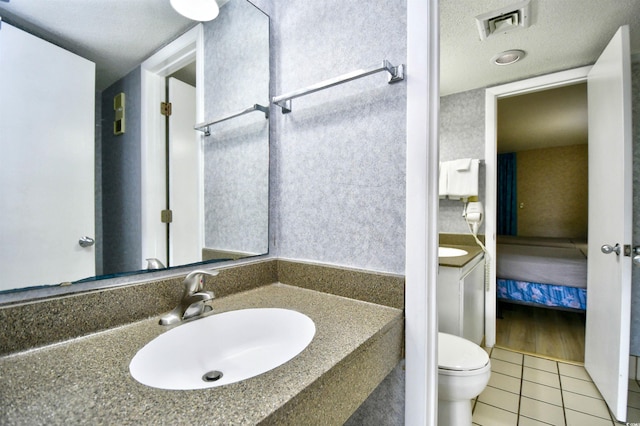 bathroom with vanity, tile patterned flooring, toilet, and a textured ceiling