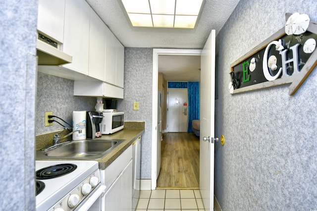 kitchen featuring sink, light tile patterned floors, white appliances, and white cabinetry