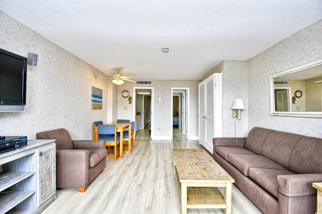 living room featuring a textured ceiling, ceiling fan, and light hardwood / wood-style flooring