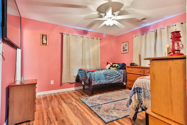 bedroom featuring ceiling fan, a textured ceiling, and light wood-type flooring